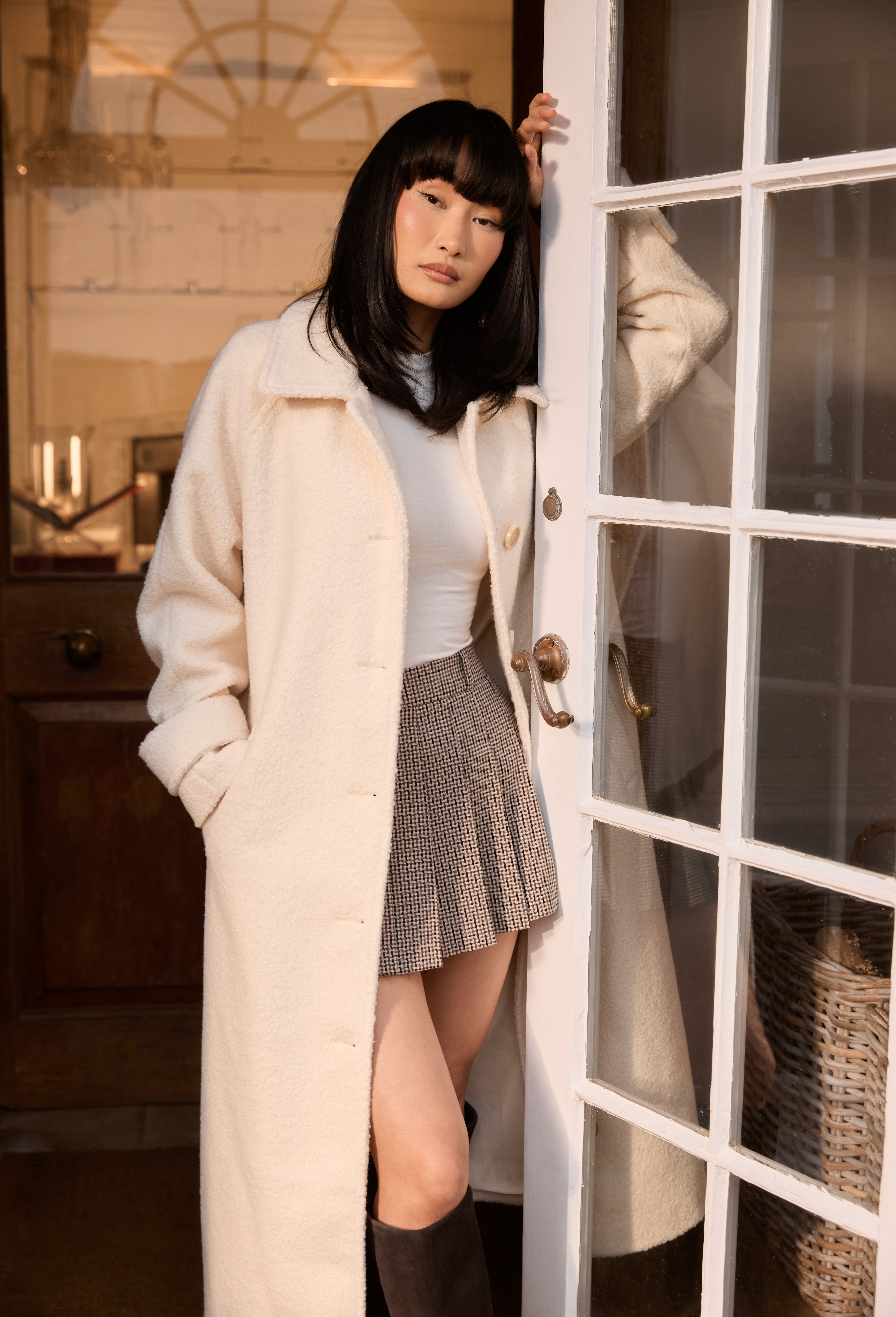 a woman in a white coat leaning against a door