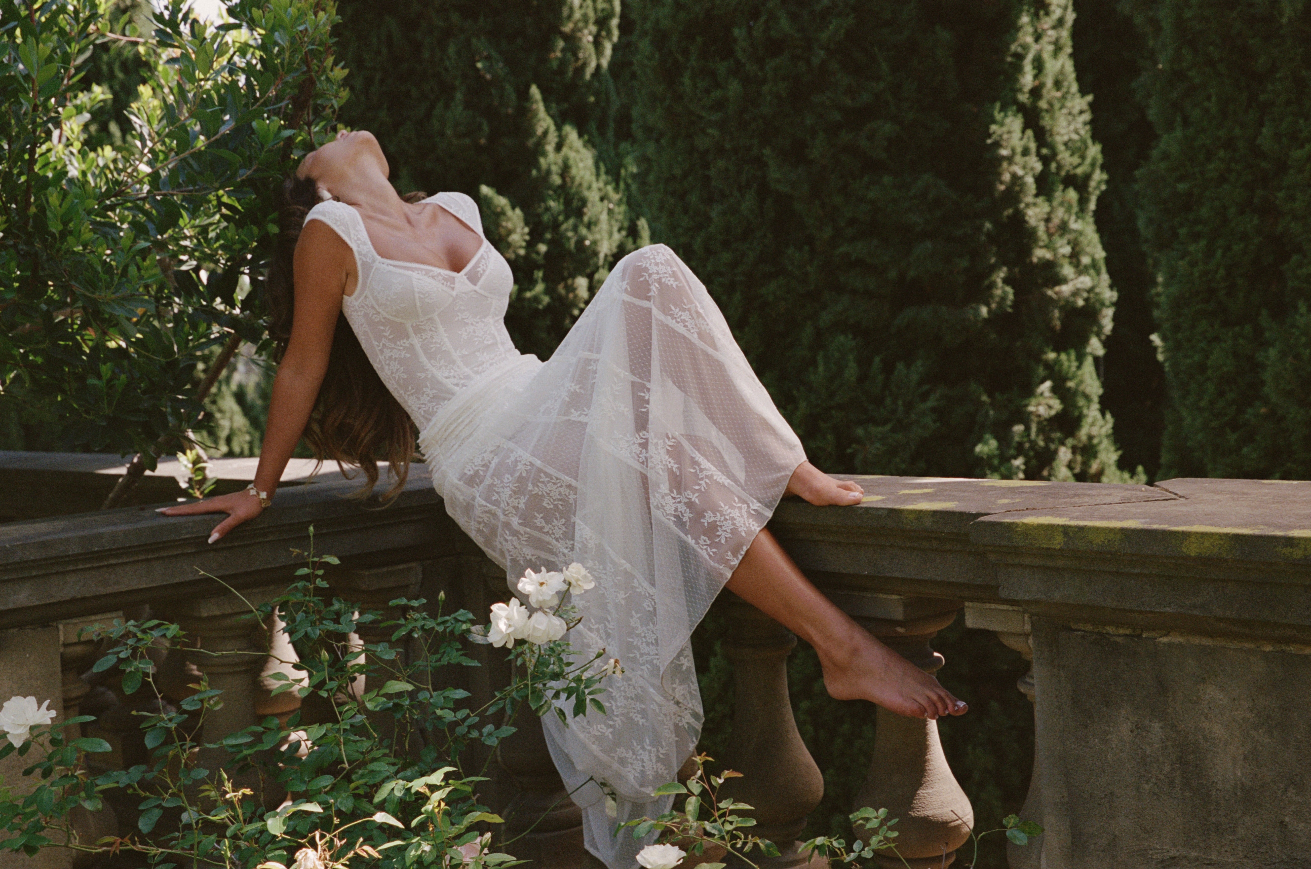 a woman in a white dress lying on a stone ledge