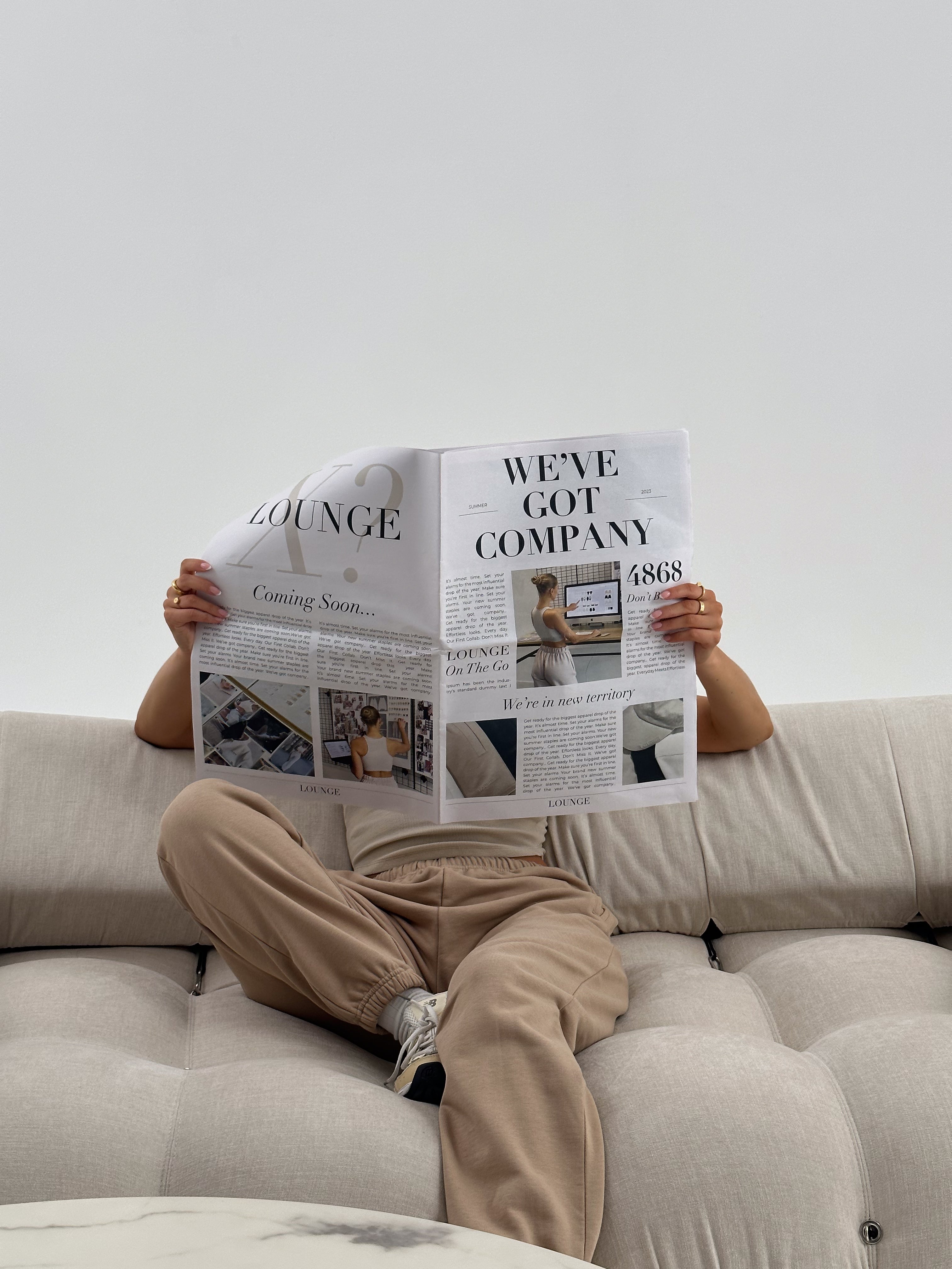 a person sitting on a couch reading a newspaper