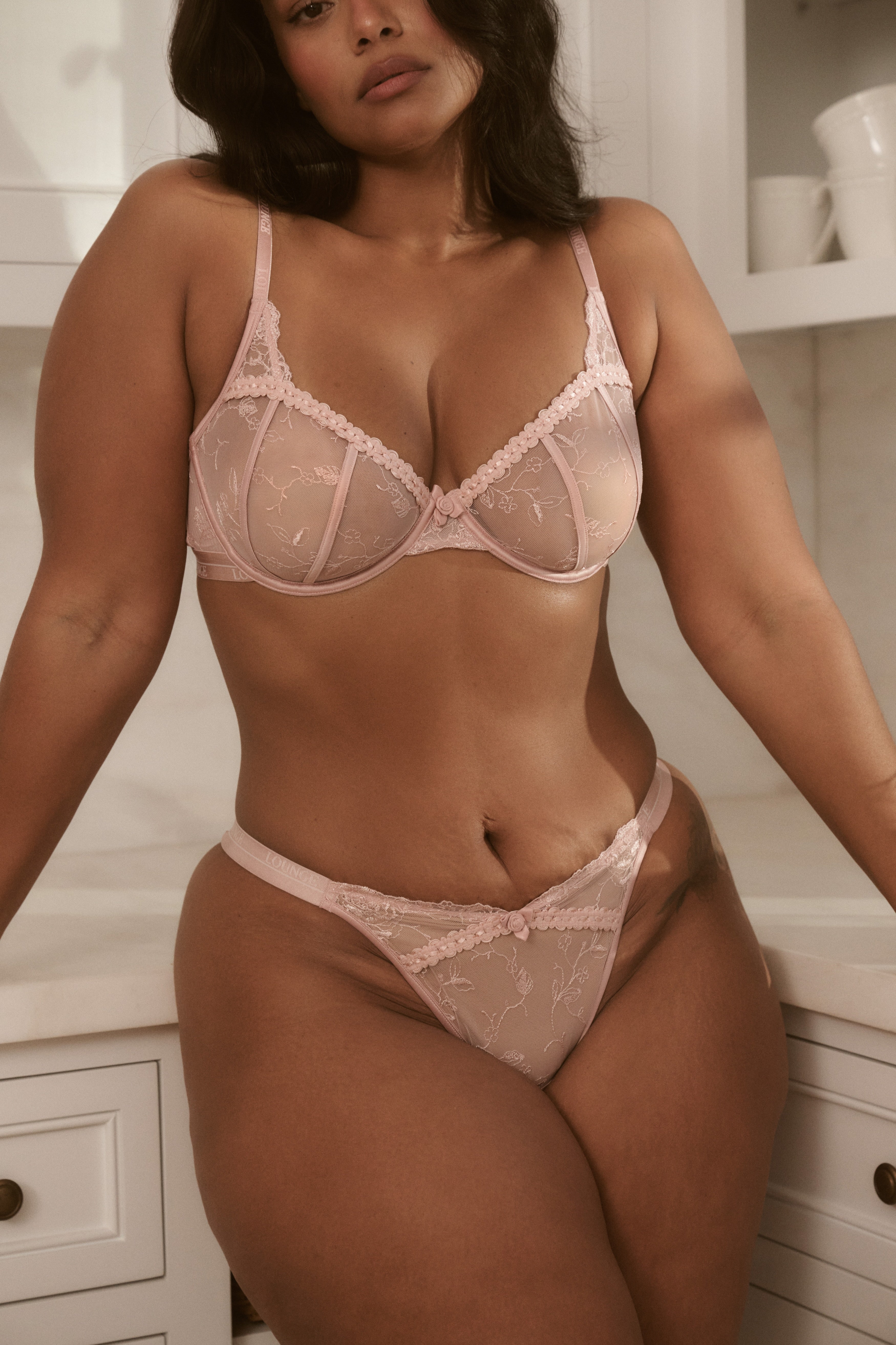 a woman wearing a pink garment and panties