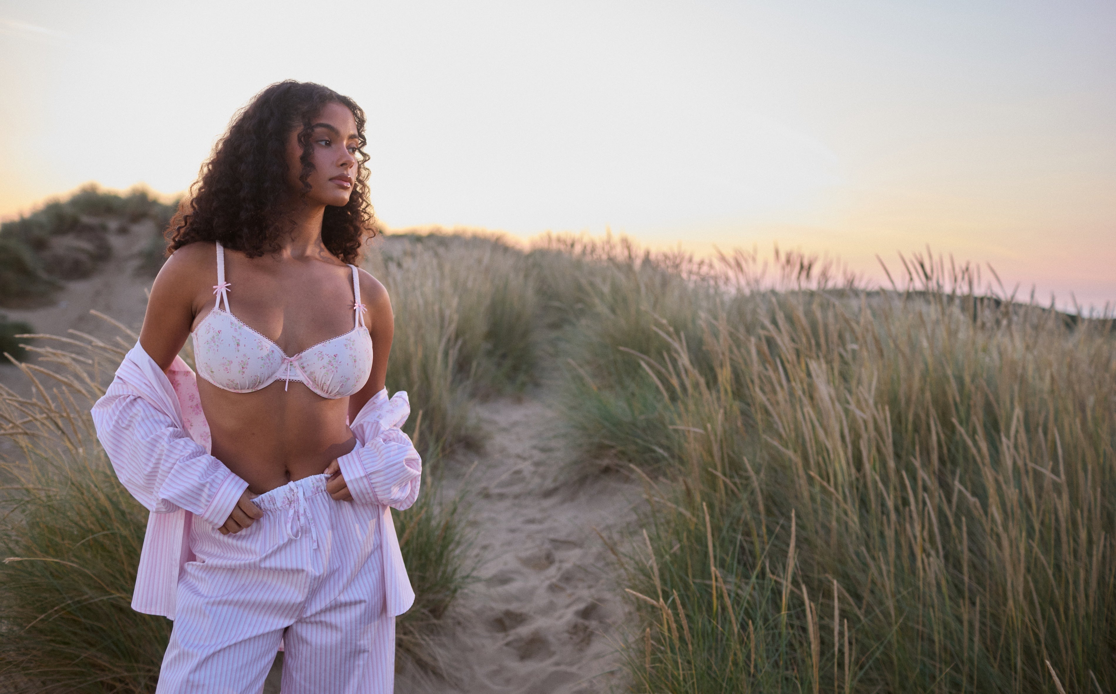a woman in a garment and pants in a grassy area
